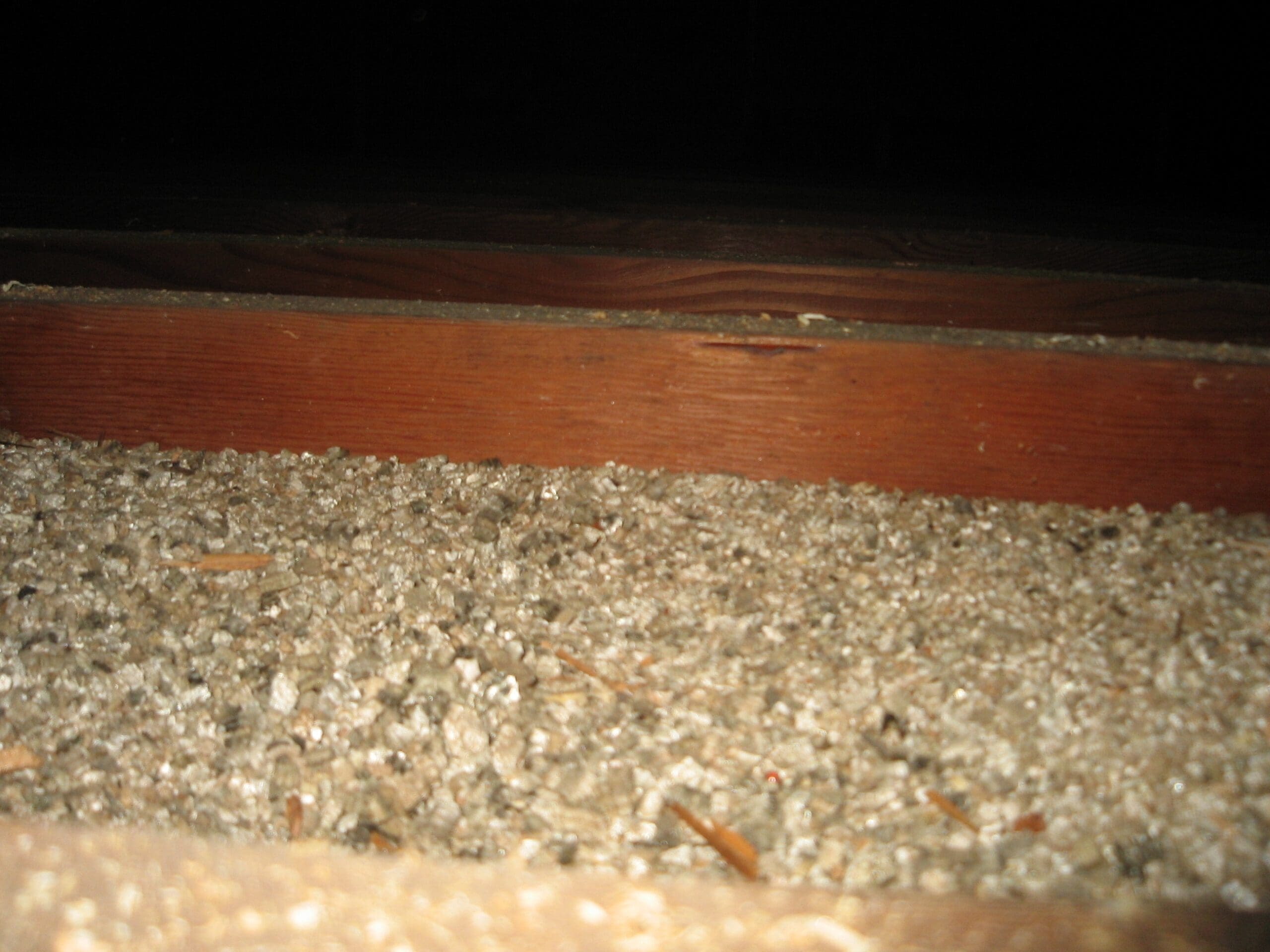 Close-up of gravel and wooden step in darkness.