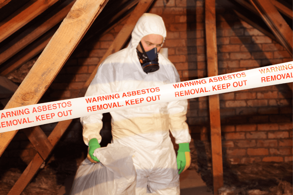 Worker in protective gear removing asbestos in attic