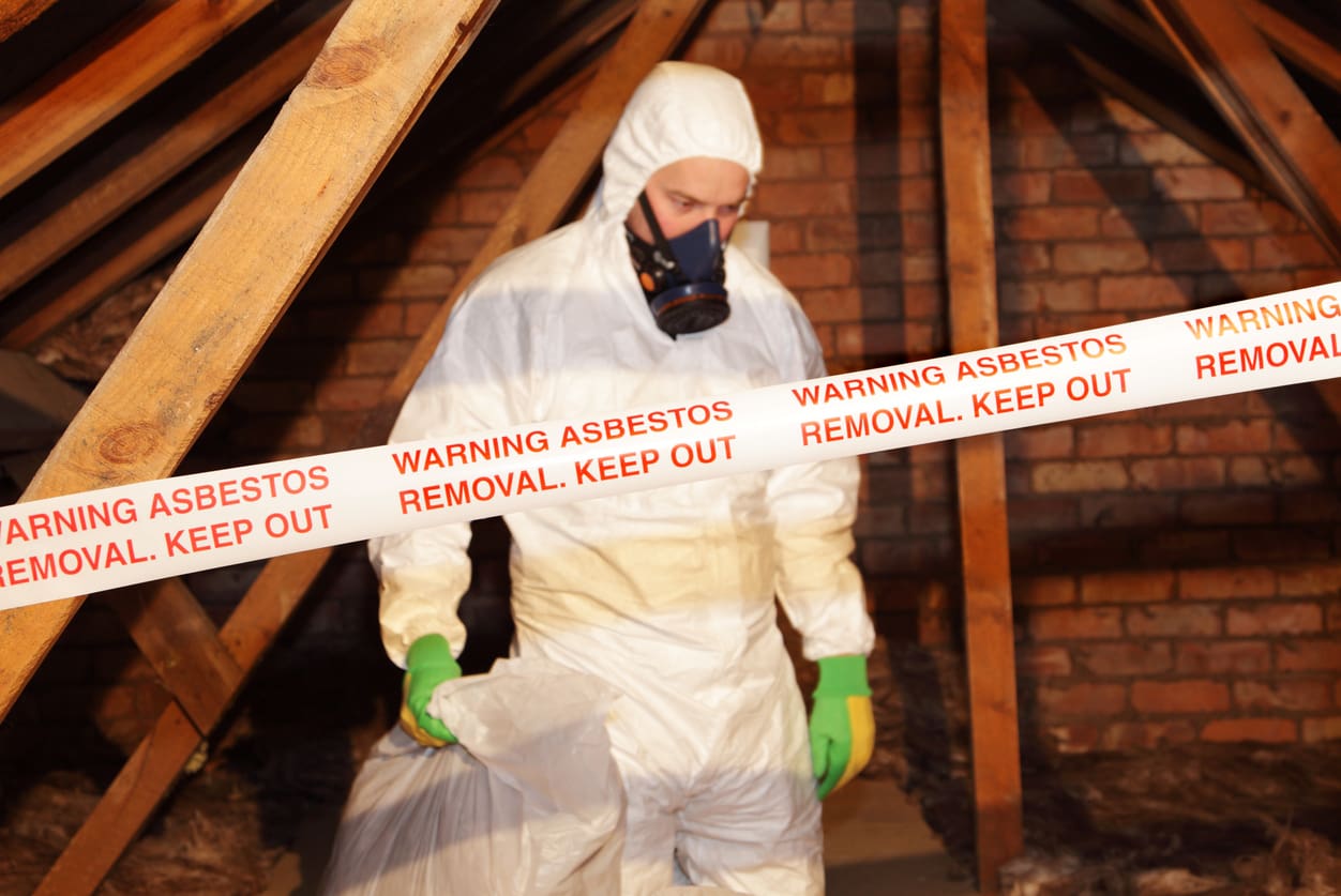 Worker in hazmat suit during asbestos removal process.