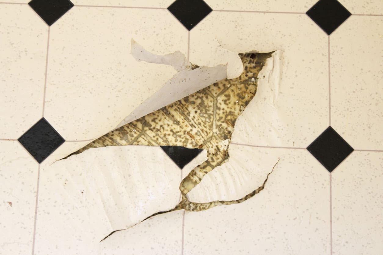 Damaged linoleum floor with peeling tiles