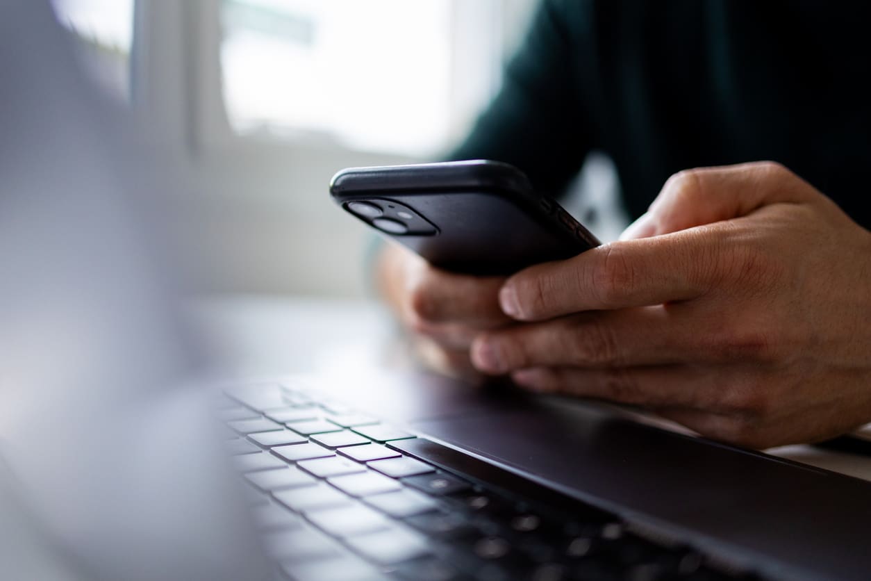 Person using smartphone and laptop together