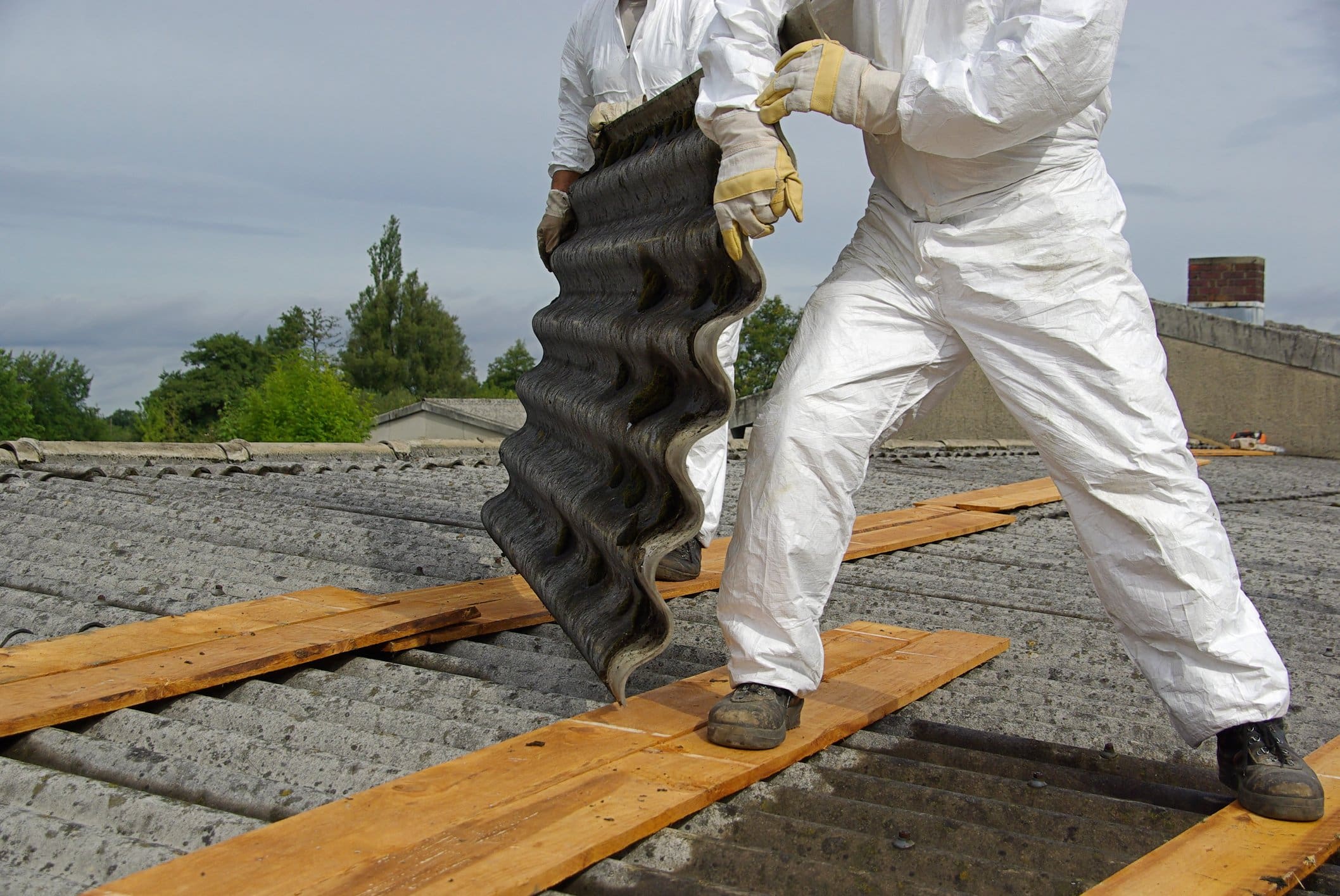 Workers removing asbestos from roof safely.