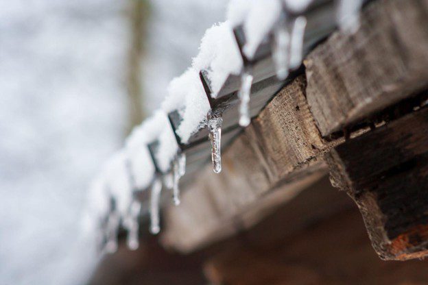 Icicles hanging from snowy wooden roof