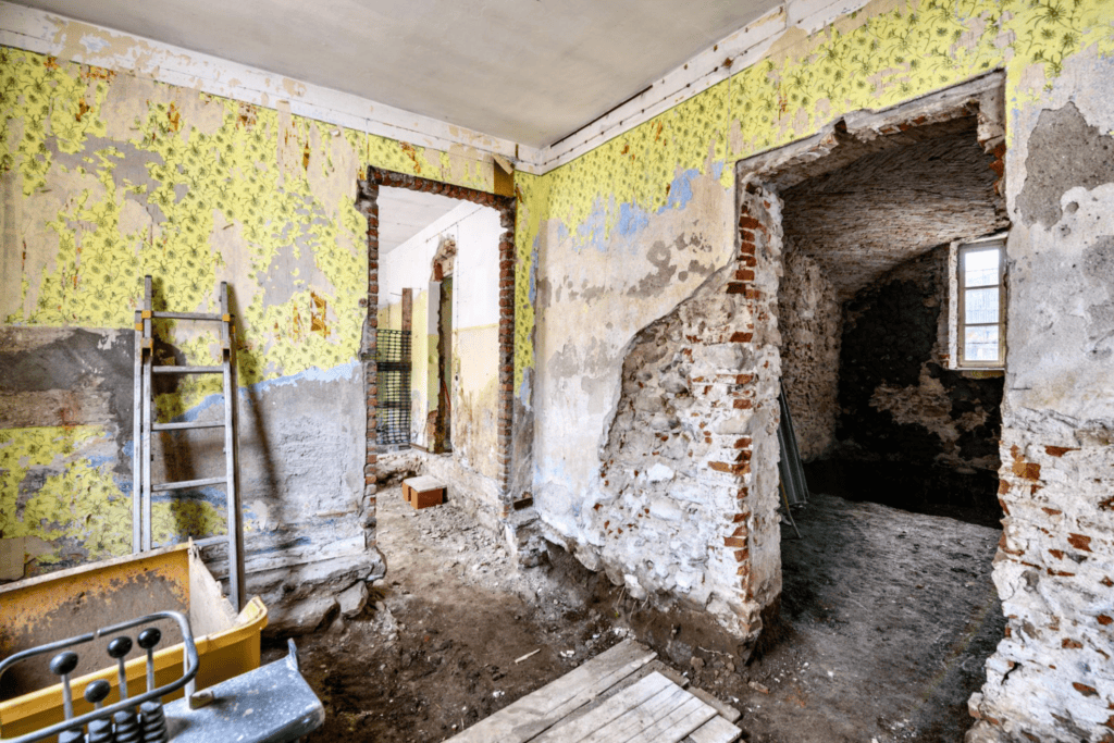 Dilapidated room with peeling wallpaper and exposed brick
